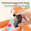 A hand is interacting with a soft orange plush dog toy, which features natural dyes and a device for sensory experience.