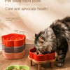 An orange ceramic slow feeder cat bowl with a wooden stand filled with pet food, next to a green bowl.