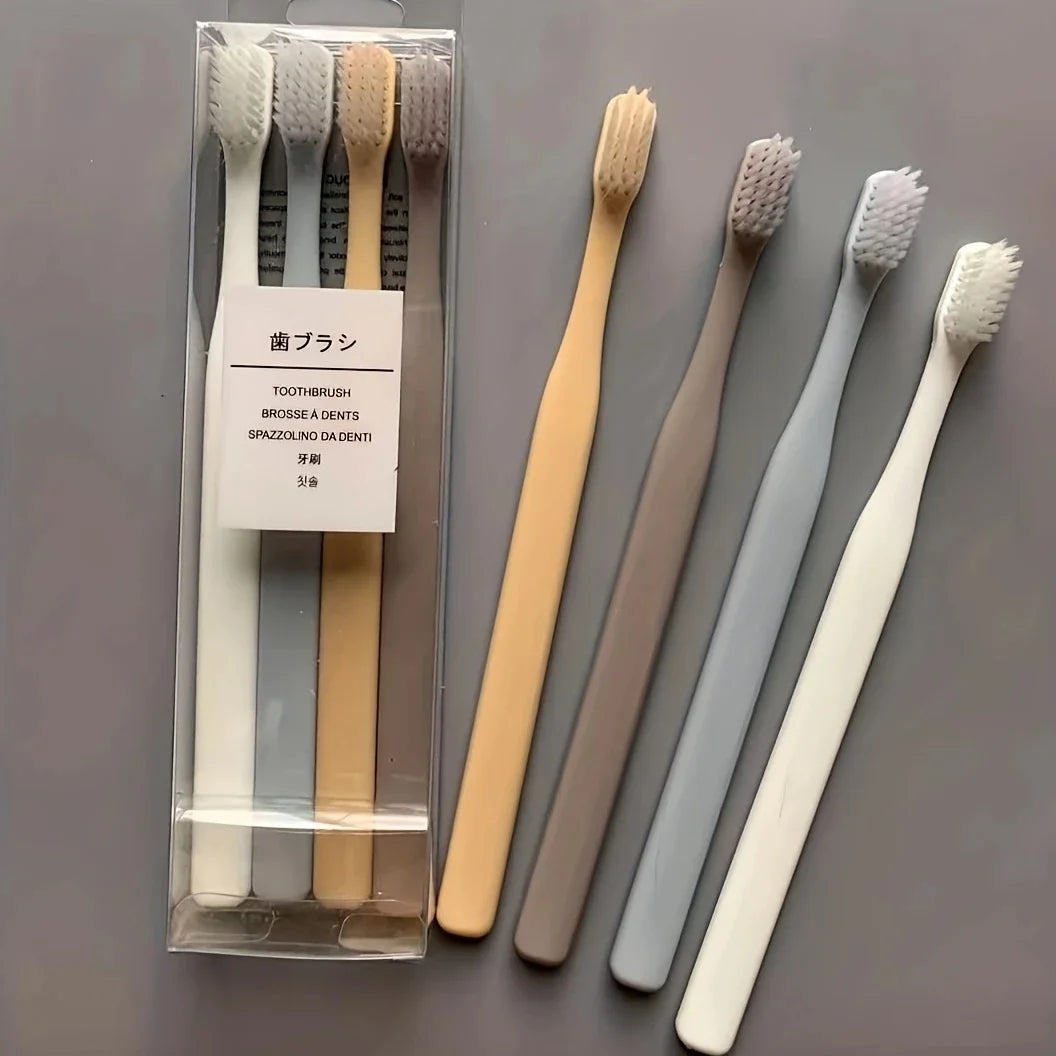 A set of four soft-bristle travel toothbrushes in various colors packaged in a clear plastic case.
