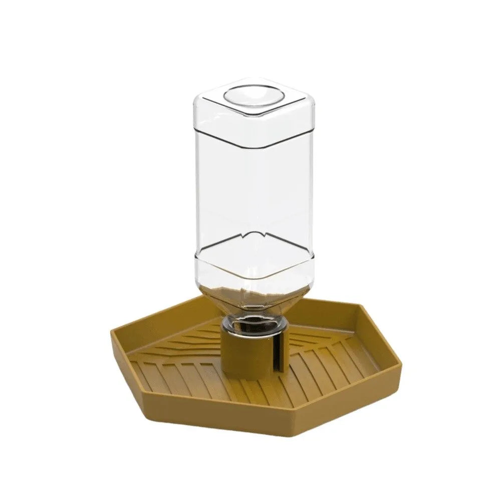 A clear automatic reptile water dispenser bowl with a yellow tray and a metal base.