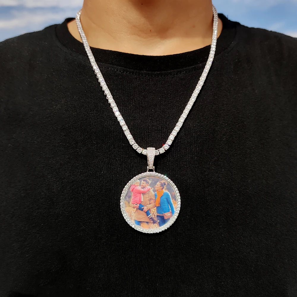 A silver-toned chain necklace with a round pendant featuring a colorful photo of people.