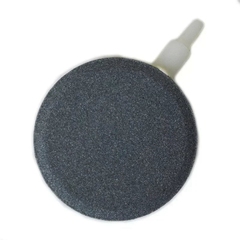 A round, dark gray air stone disc with a white nozzle for aquarium oxygenation.