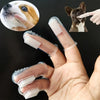 A hand holds a silicone finger toothbrush designed for dogs and cats, with a dog's face visible in the background.