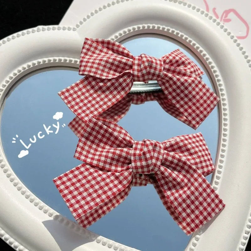 A red and white plaid fabric bow is displayed in a heart-shaped mirror frame.