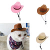 A white cat wearing a pink adjustable cowboy hat with gold trim and a purple patterned bandana.