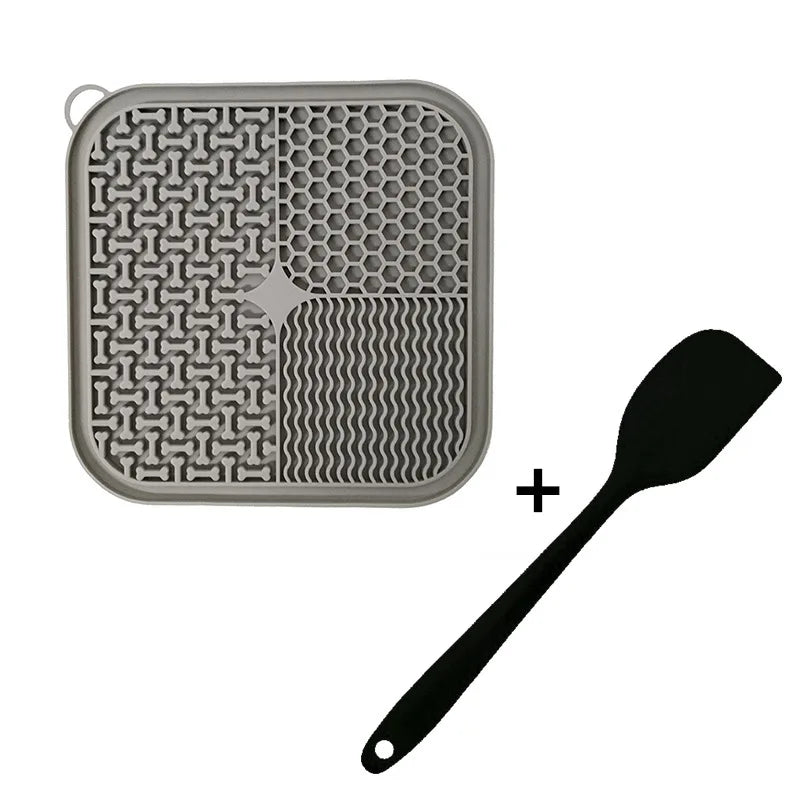 A silicone licking mat for pets featuring a textured surface and suction cups, shown next to a spoon.