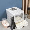 A white foldable cat litter box with a front entry and top exit is shown on a gray floor.