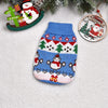 Blue knitted dog sweater with festive red and white patterns, displayed next to Christmas ornaments.