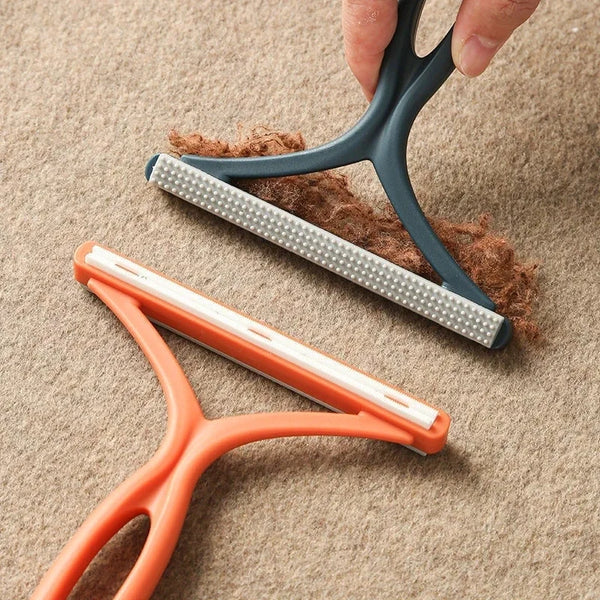 A hand is holding an orange 2-in-1 pet hair remover and fabric shaver against a beige background.