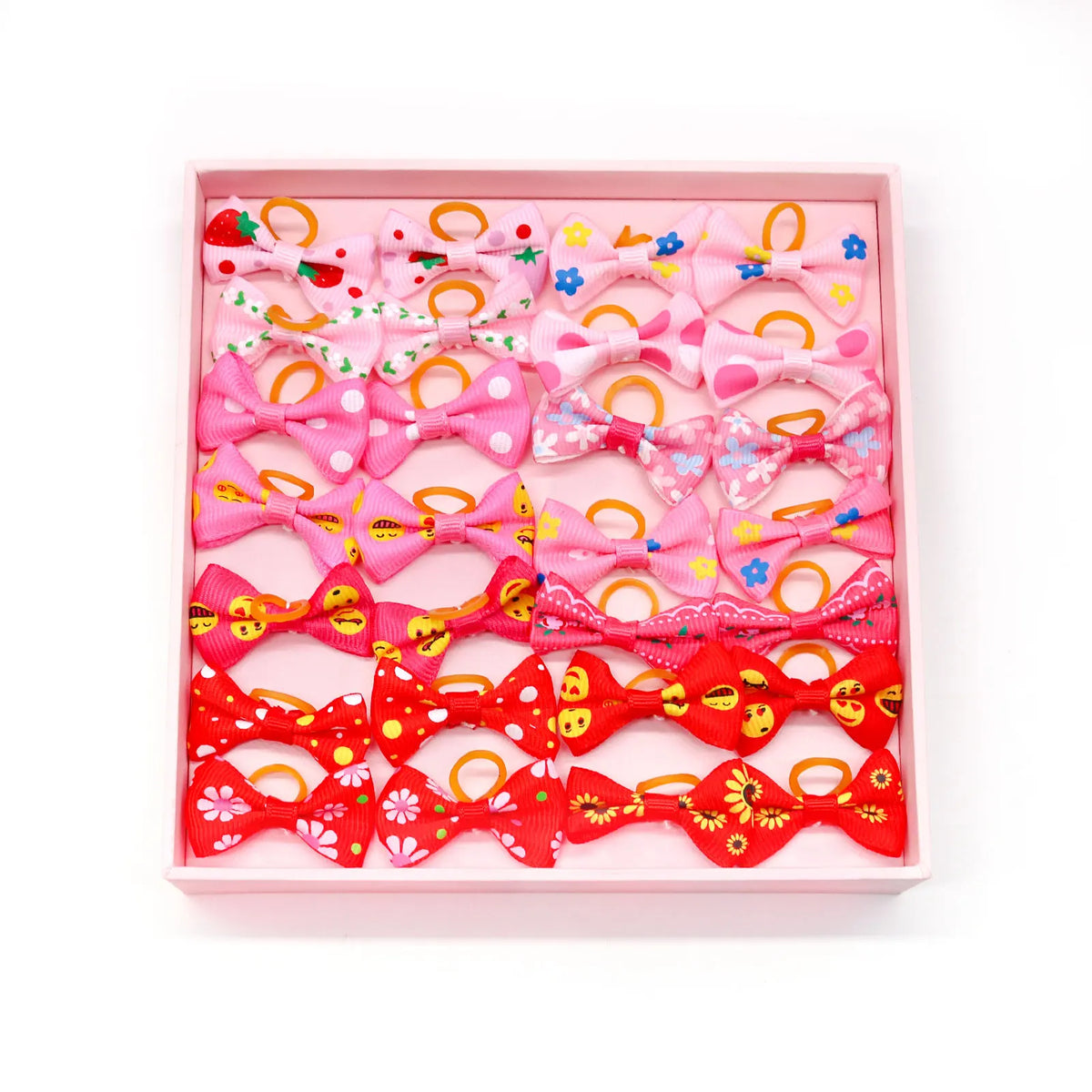 A pink tray filled with various adorable pet hair bows in shades of pink, red, and orange.