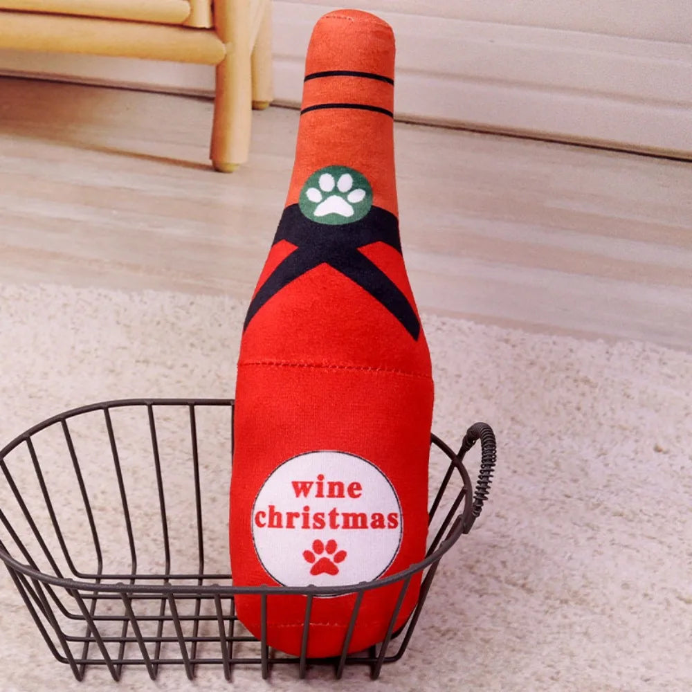 An orange bottle-shaped squeaky plush dog toy with a green paw print design sitting in a wire basket.