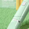 A close-up view of a light green pet grooming tool with a cutting head, lying on green grass.