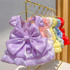 A purple solid color pet dress with a large bow and D-ring hanging on a gold hanger.