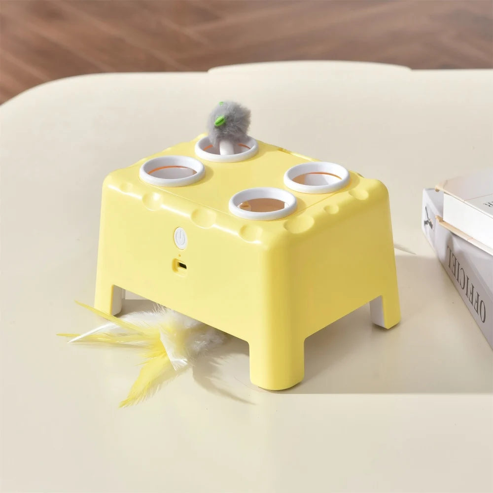 Gelbes automatisches Spielzeug mit mehreren Futterbechern und einem flauschigen Federchen auf einer hellen Oberfläche.