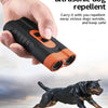 A hand holds a black ultrasonic dog repellent device, with a dog running in the background.