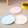A set of pink, blue, and cream silicone feeding plates and a yellow bowl on a wooden surface.