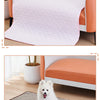 A fluffy white dog is sitting on a pink quilted washable cooling mat for dogs.