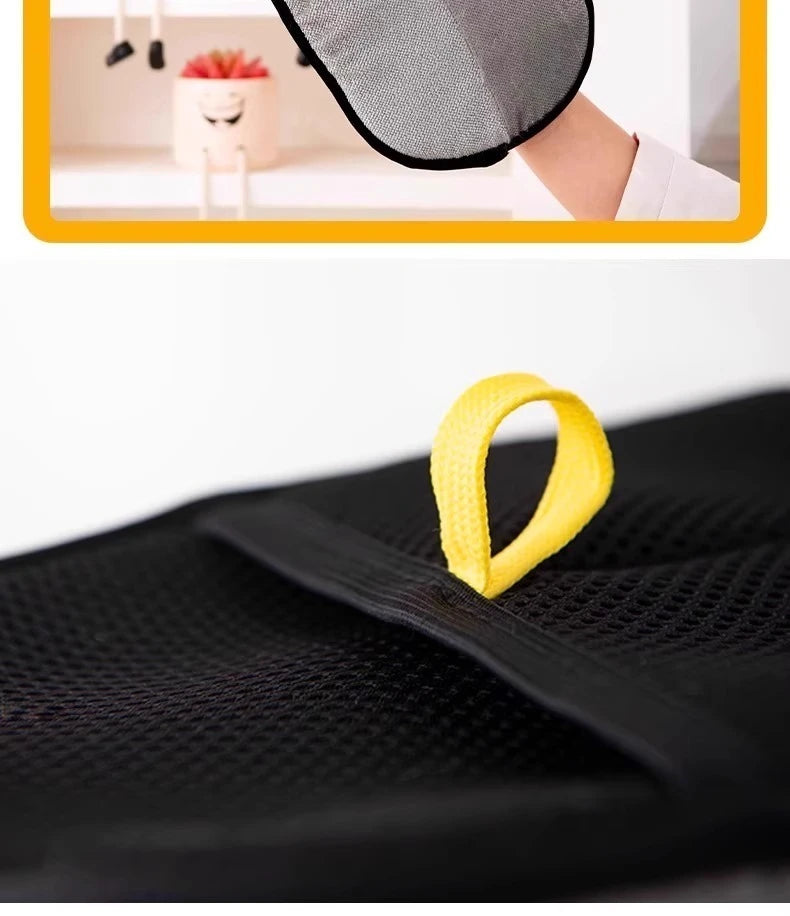 Yellow reusable pet grooming glove being worn on a hand against a black mesh fabric.
