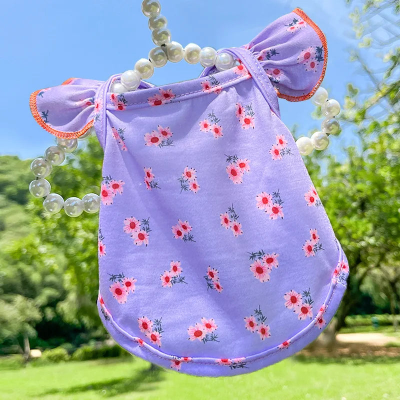 A purple summer dot pet dress for a small dog with white pearl trim and floral embroidery, outdoors.