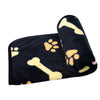 Black pet mat featuring yellow paw prints and bones, rolled up for storage.