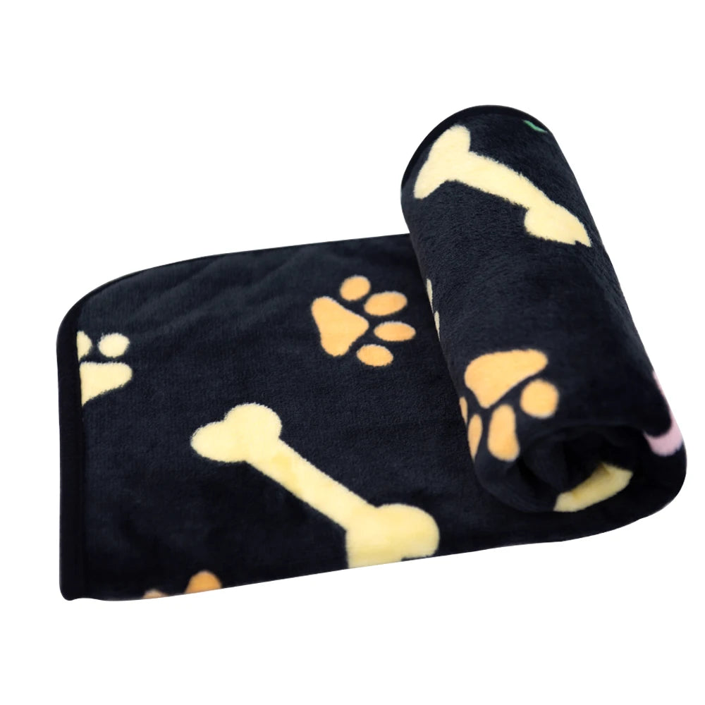 Black pet mat featuring yellow paw prints and bones, rolled up for storage.