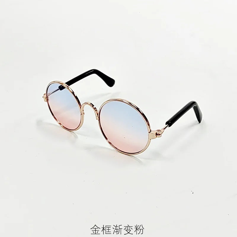 Round gold-toned sunglasses with pink gradient lenses and black frames