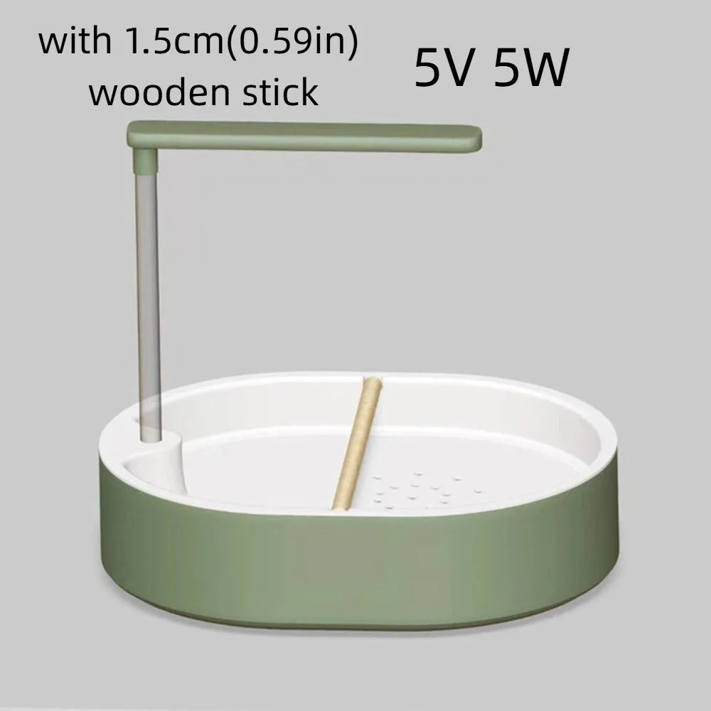 A light green automatic bird bathtub with a resting stick and a wooden stick inside.