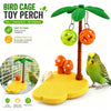 A green tropical bird cage toy perch with hanging balls and a yellow play mat for birds