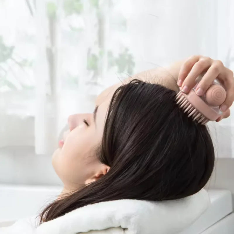 A woman is using a soft silicone pet bath brush with shampoo dispenser on her hair.