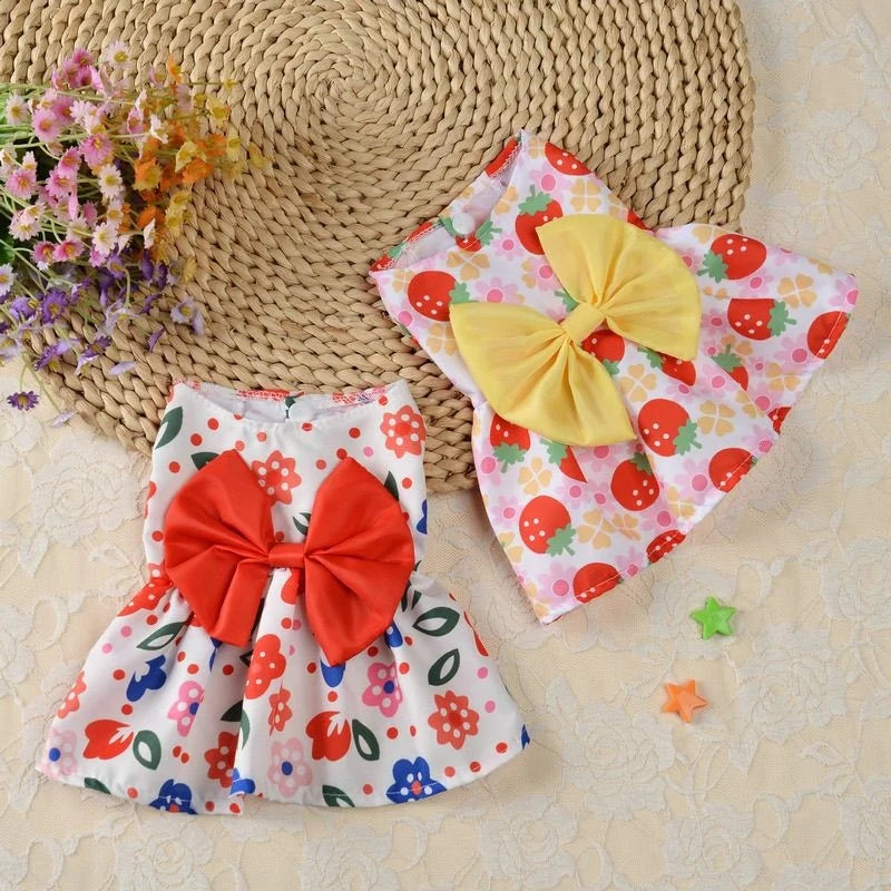Une robe d'été rose et blanche avec un nœud orange est présentée sur un tapis tissé à côté d'un nœud en tissu jaune.
