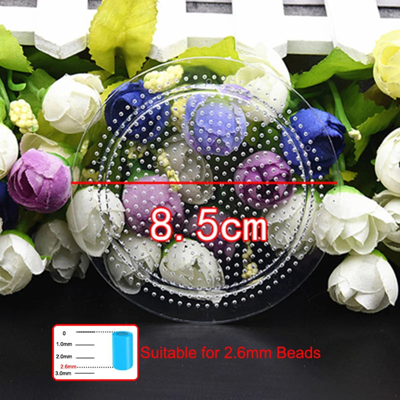 A clear petri dish filled with white and purple flowers and small beads, demonstrating a scale for 2.6mm beads.