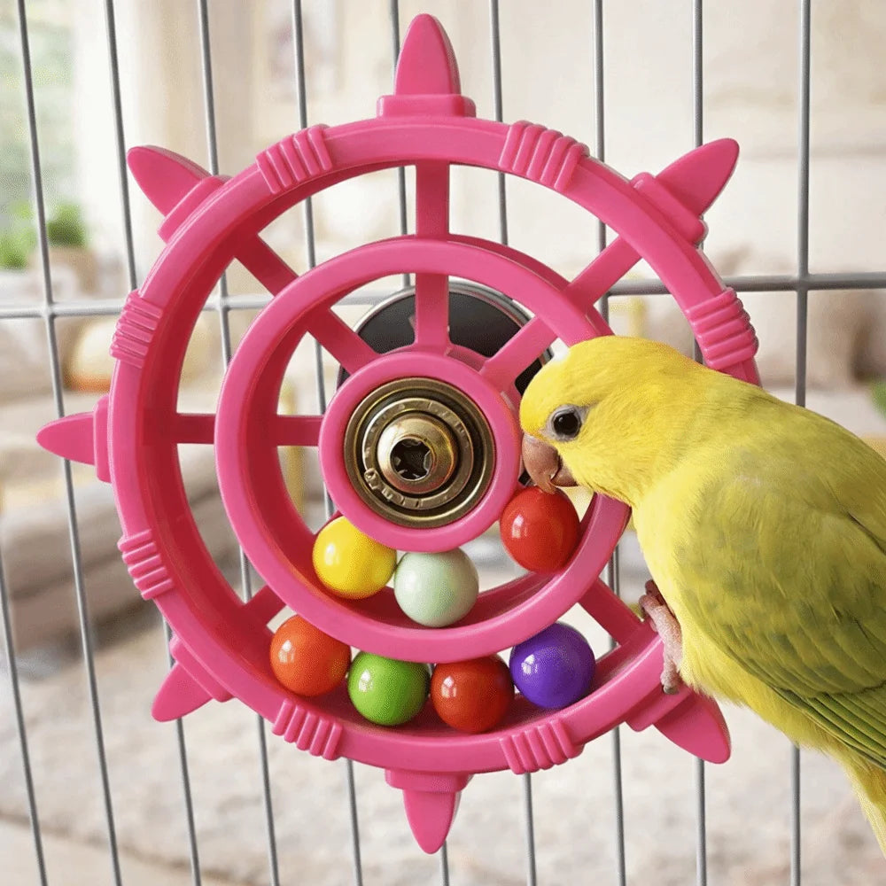 A yellow parrot is interacting with a pink, circular spinner rattle toy inside a wire cage.