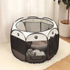 A black and white folding octagonal pet cage for dogs sitting on a light rug.