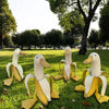 A garden sculpture of a white resin banana duck with yellow accents sitting on green grass.