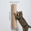 A tabby cat is climbing a cylindrical scratching post mounted on a white wall.
