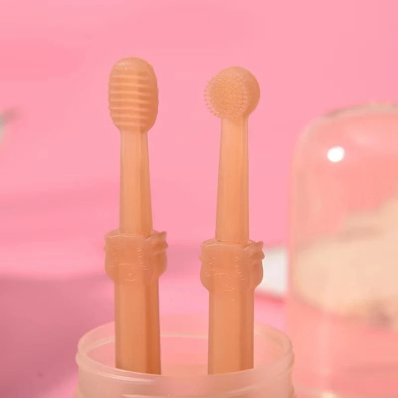 A pair of peach-colored silicone pet toothbrushes with bristles are shown standing in a clear container.