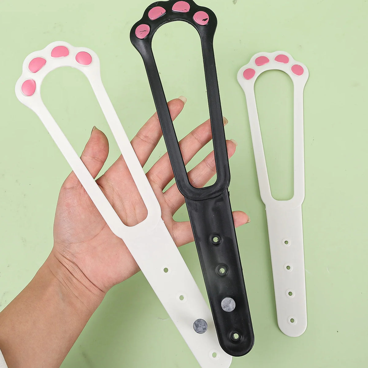 Eine Hand hält eine verstellbare Pet-Tür-Verriegelung und Stopper mit weißen und schwarzen Komponenten.