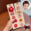 A hand holds a package of five adorable flower-shaped baby hair clips in various colors and textures, displayed next to a pho
