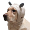 A light-colored dog wearing a beige knit ear muff with gray ears.