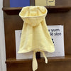 A yellow multi-purpose pet bath robe for dogs hanging on a wooden shelf.
