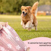 A golden retriever dog is running in a grassy field next to a pink biodegradable poop bag.