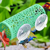 A green aquarium hideout tube with suction cups is shown in a natural, leafy outdoor setting.