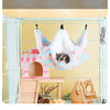 A fluffy pink and blue plush hammock is hanging inside a wire cage, designed for convenient entry and exit of small pets.