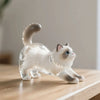 Figurine de porte-clés en résine d'un chat blanc sur une surface en bois.