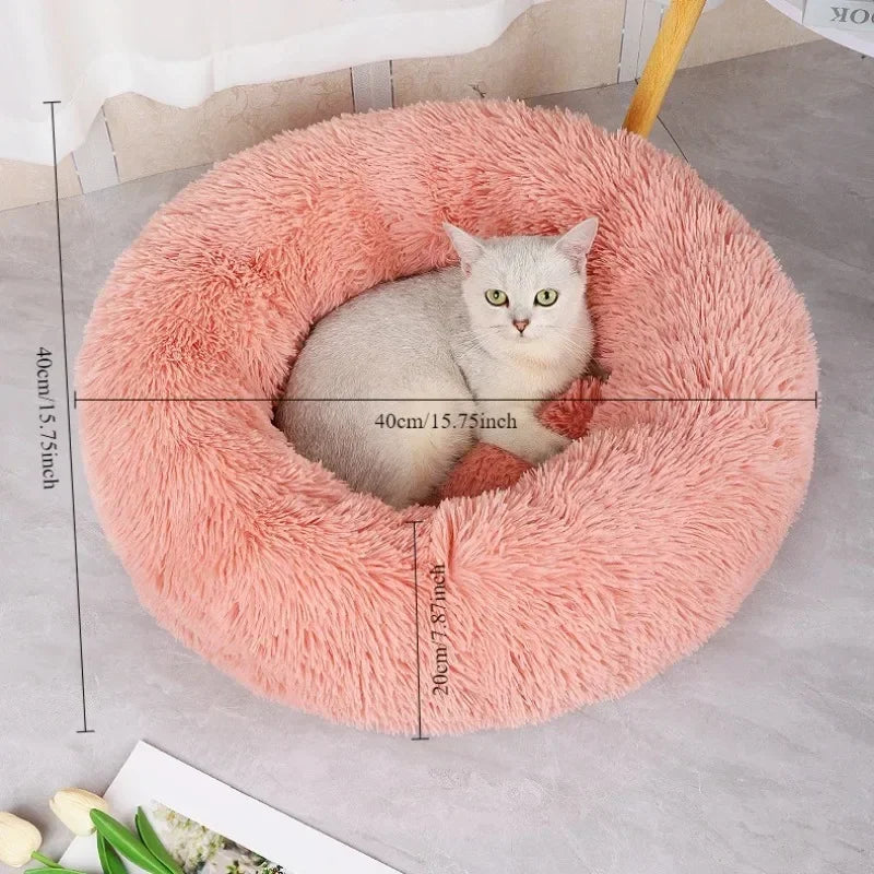 A fluffy pink round faux fur bed with a cat sitting inside, showing its dimensions.
