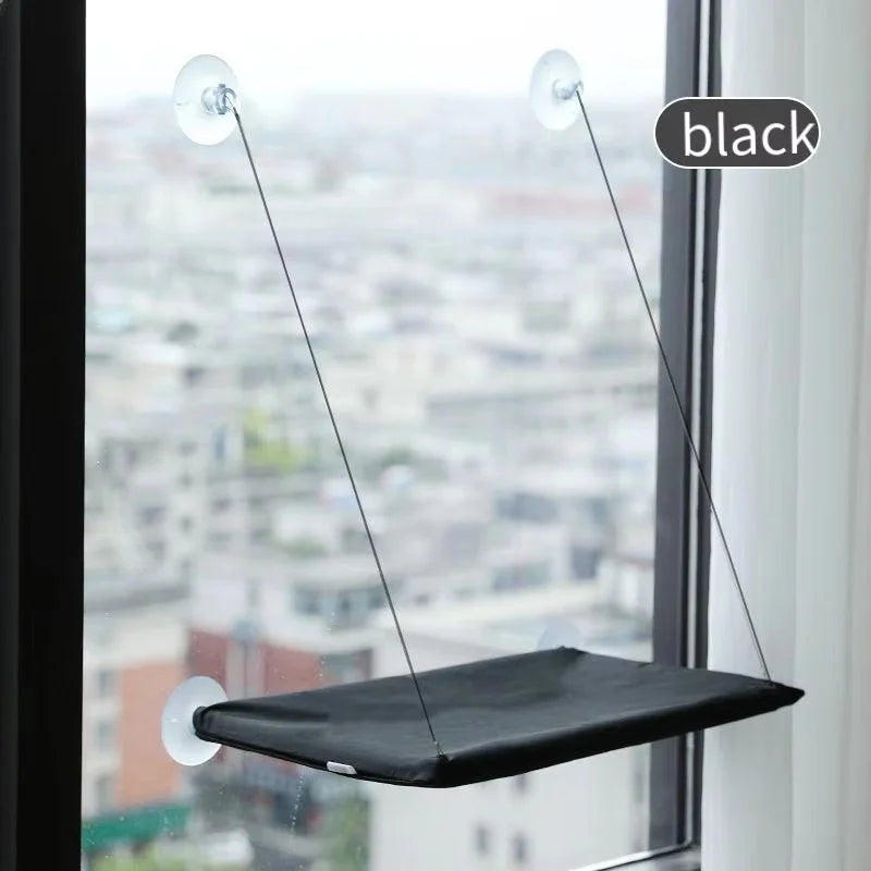 Black suction cup window hammock bed suspended by thin wires in a window frame.