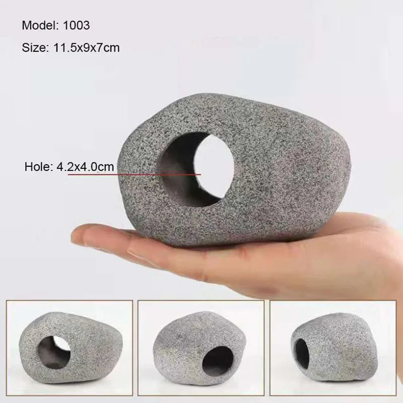 A hand holds a gray ceramic cichlid cave aquarium decor piece with a circular hole.
