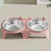 A pink stainless steel double pet bowl with an anti-tip design sitting on a light surface.