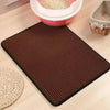 A dark brown, textured cat litter mat with a waterproof base is shown on a light wooden surface.