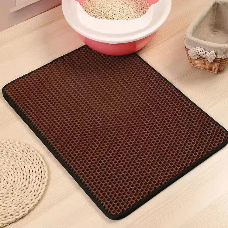 A dark brown, textured cat litter mat with a waterproof base is shown on a light wooden surface.